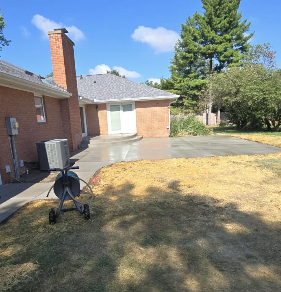 Freshly poured concrete patio behind a brick house on a sunny day
